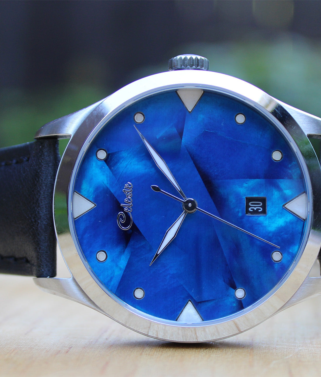 Watch with cobalt blue face and black strap on a blurred background