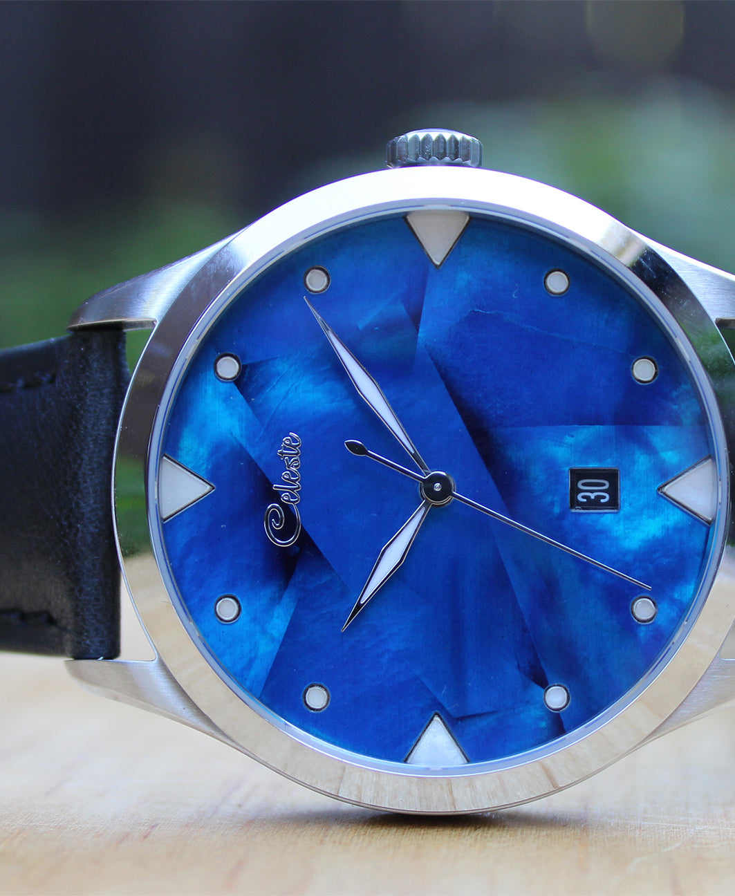 Watch with cobalt blue face and black strap on a blurred background