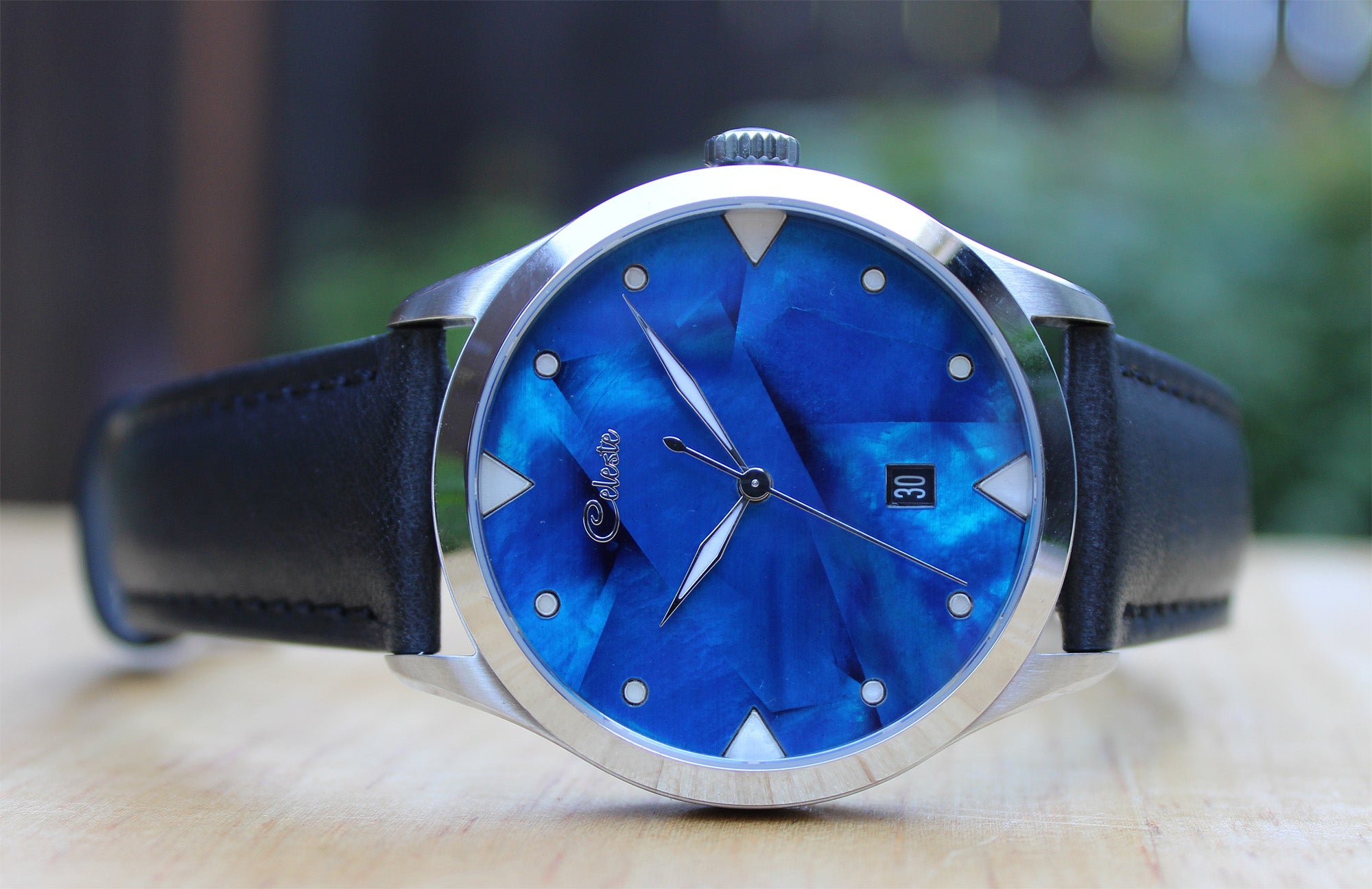 Watch with cobalt blue face and black strap on a blurred background